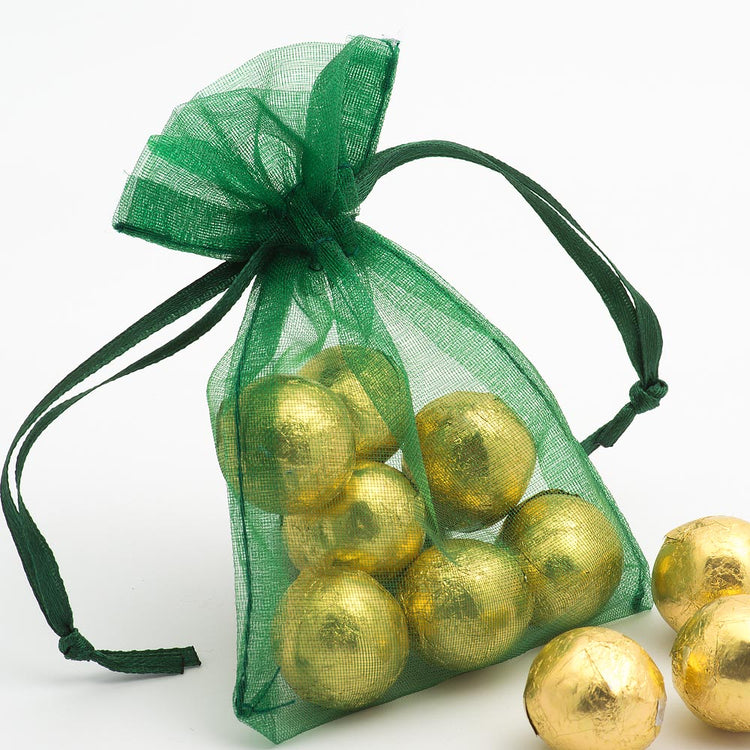 Green organza bag filled with gold foil covered chocolate sweets for wedding favours