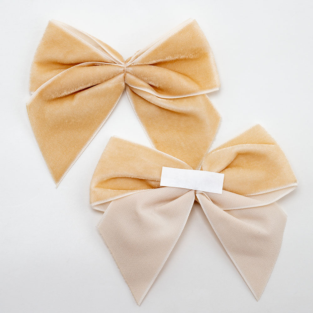 Front and back of champagne gold 10cm velvet bows showing the self-adhesive strip