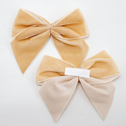 Front and back of champagne gold 10cm velvet bows showing the self-adhesive strip