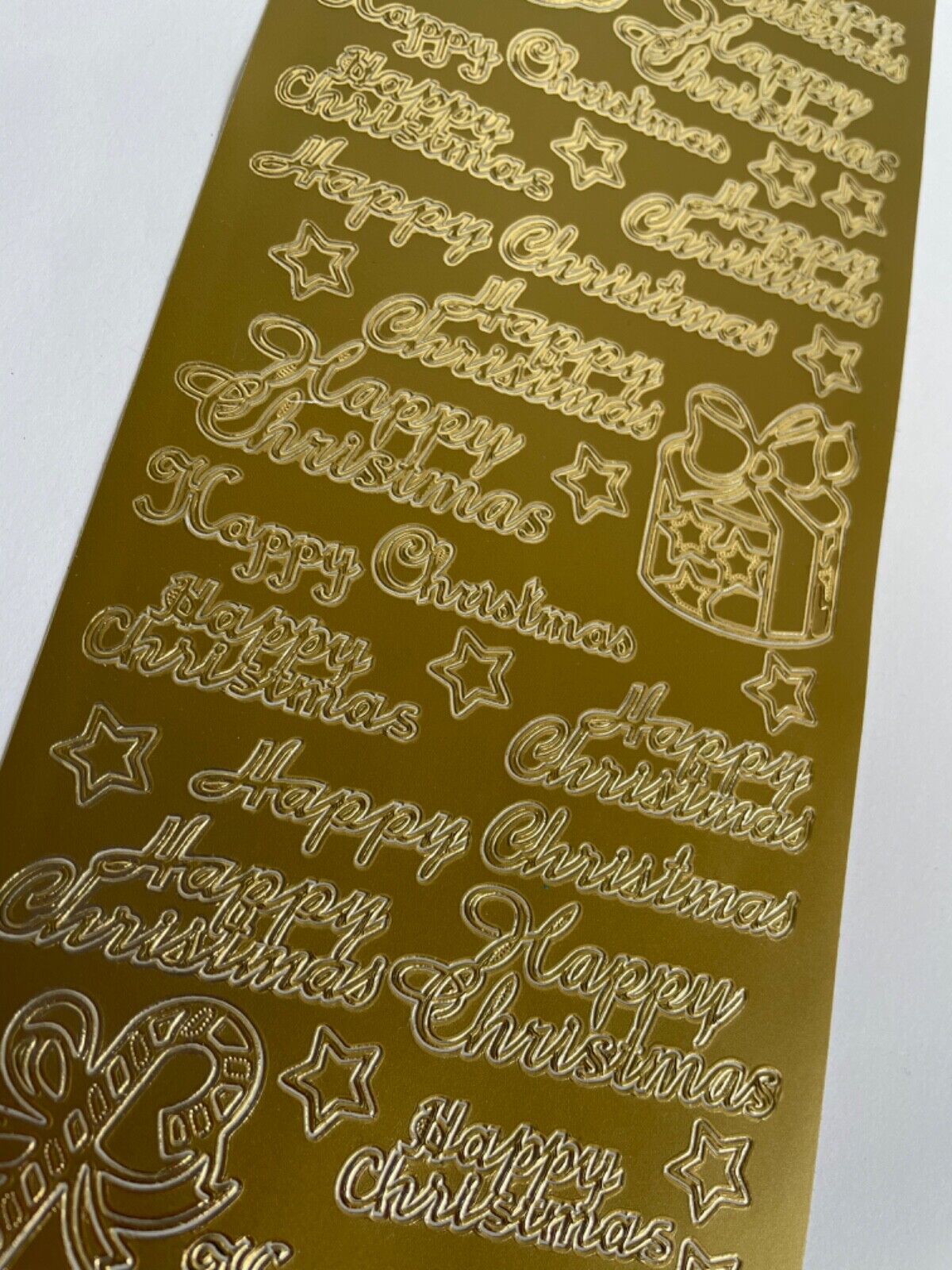 Close-up of gold Happy Christmas peel off greetings for handmade cards