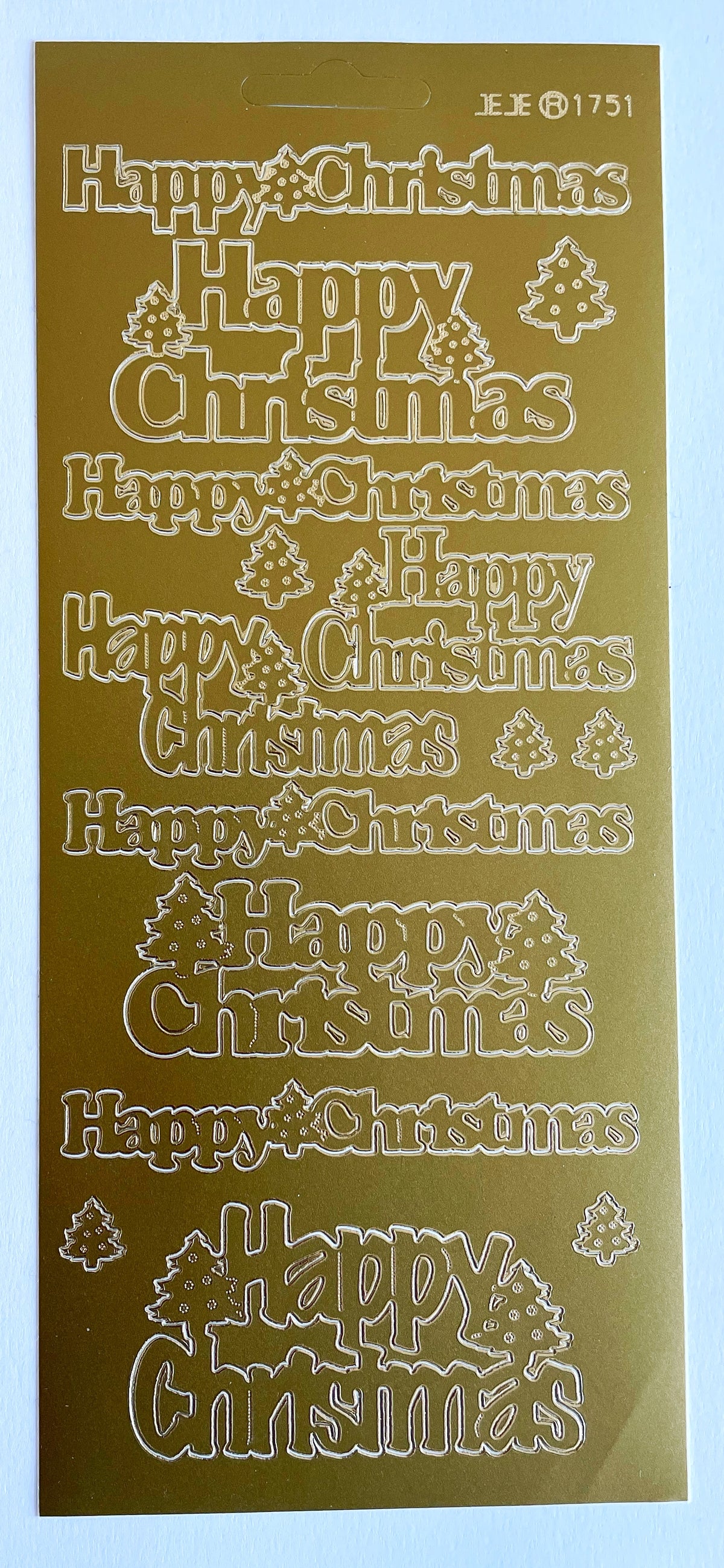 A gold-colored peel off sticker sheet featuring multiple repeated 'Happy Christmas' phrases in various decorative fonts, along with small Christmas tree illustrations.