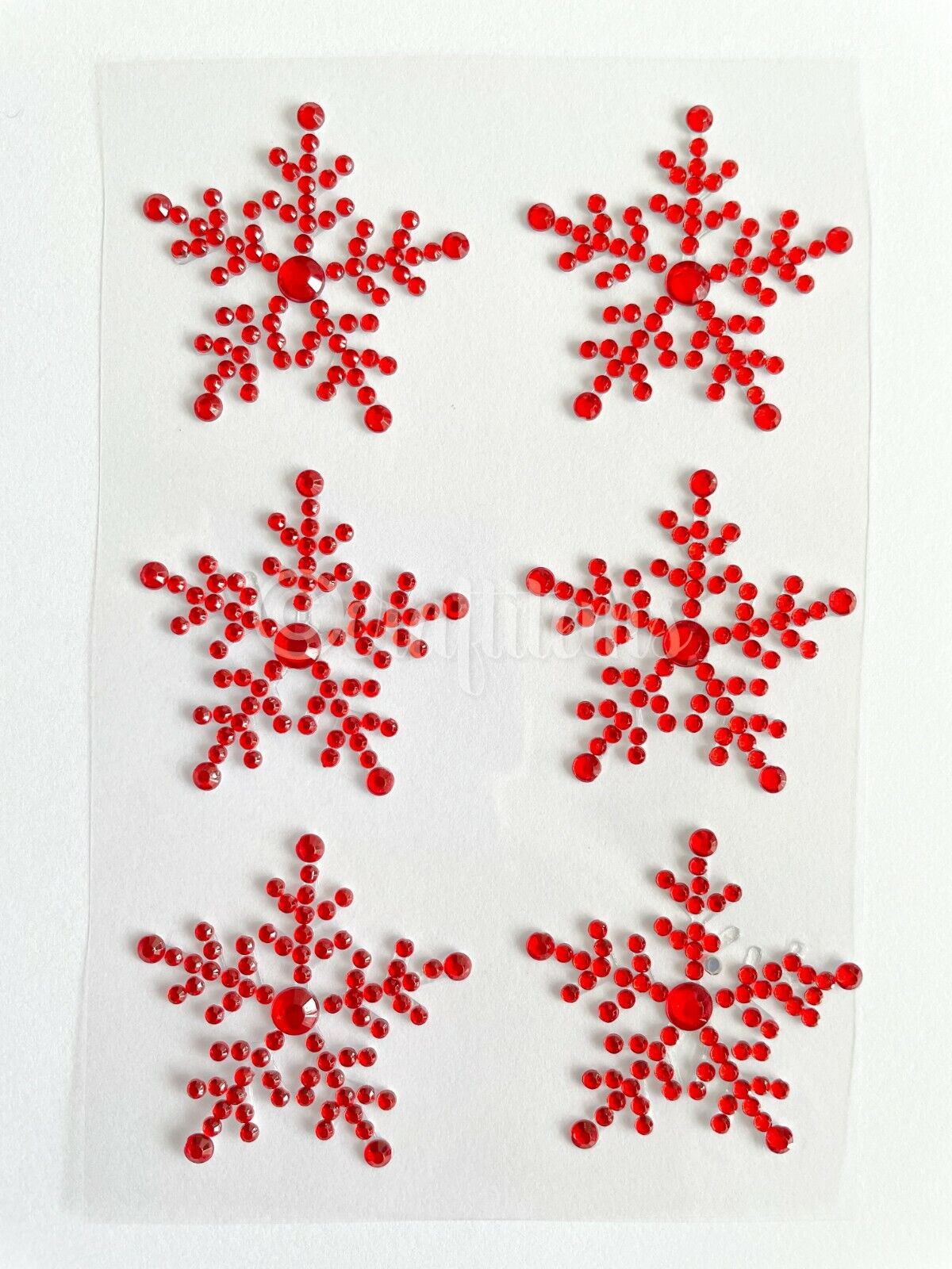 Six red snowflakes stickers on a sheet made from gems for decorating Christmas cards