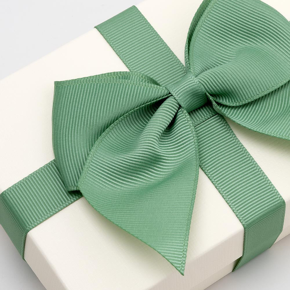 Large sage green grosgrain gift bow decorating a white gift box
