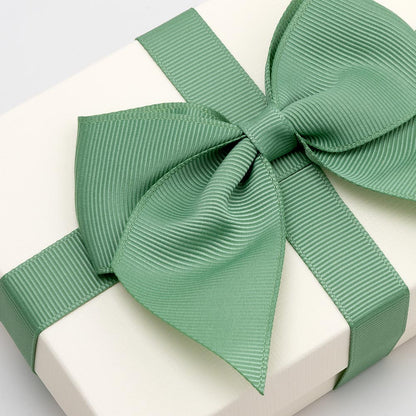 Large sage green grosgrain gift bow decorating a white gift box